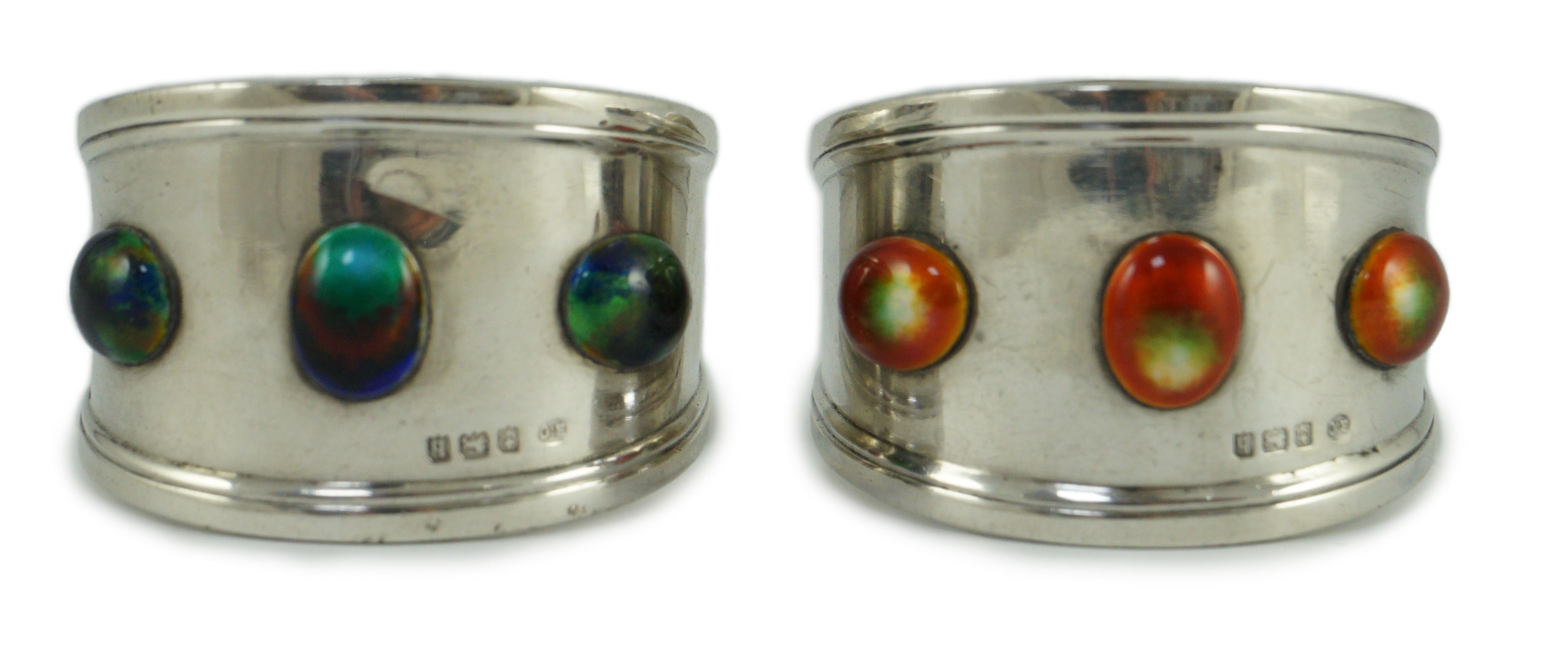 Two similar Edwardian Arts & Crafts silver and enamelled napkin rings